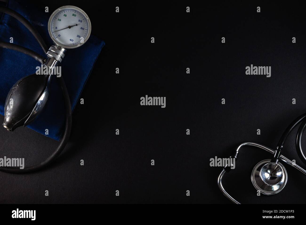 Vecchio monitor del misuratore di pressione sanguigna e phonendoscopio stetoscopio isolato su sfondo nero. Concetto di assistenza sanitaria, vista dall'alto. Foto Stock
