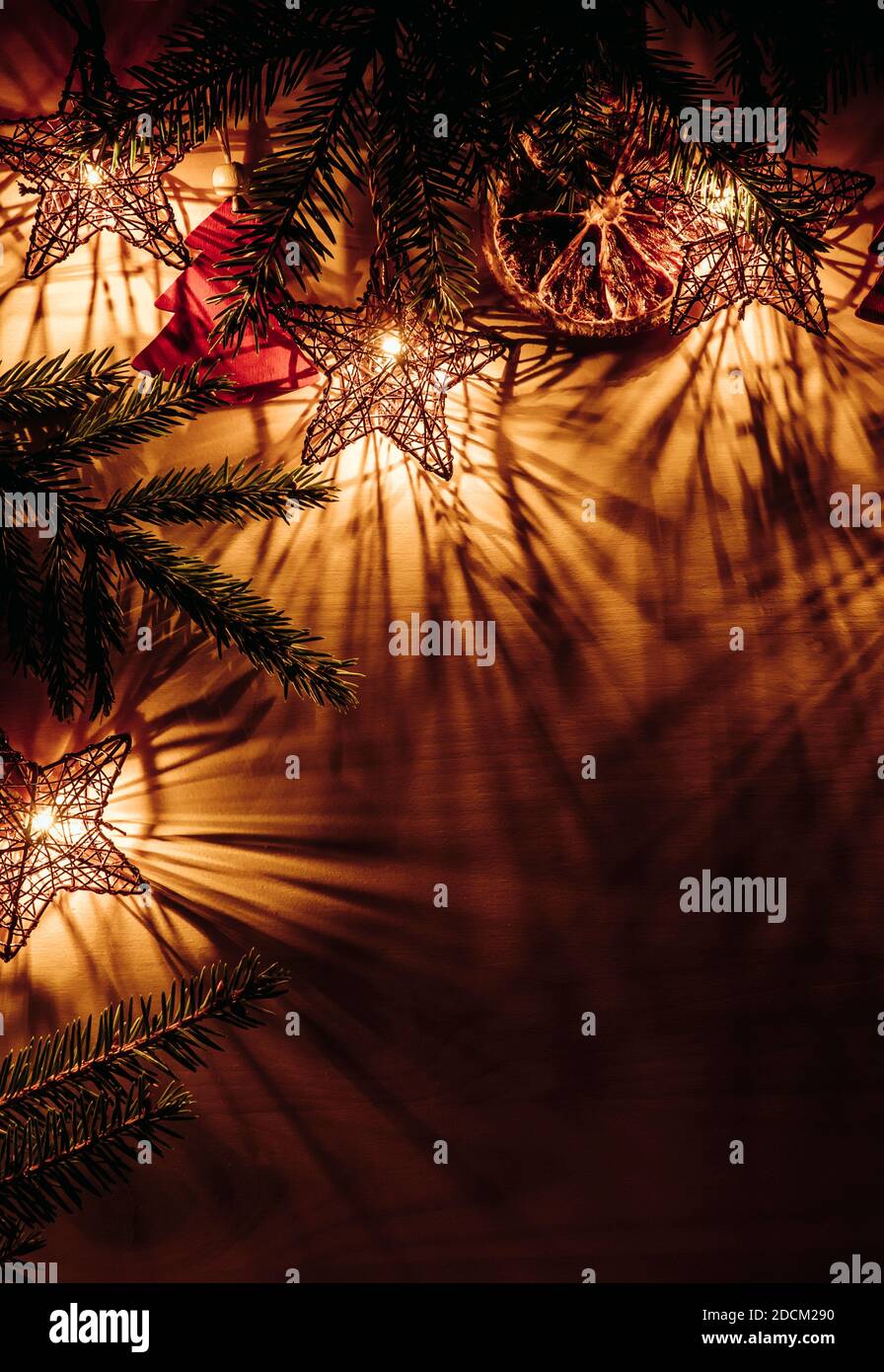 Sfondo di Natale, bordo superiore con rami di abete rosso forma stella luci partito illuminato, a fette arancio secco e figurine a forma di albero rosso. Foto Stock