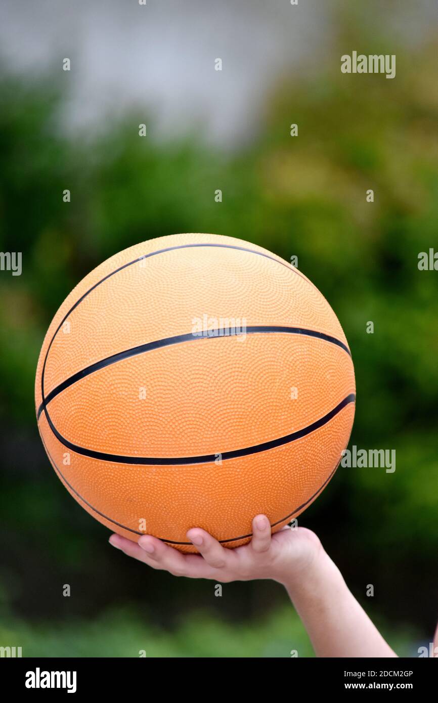 Una mano che tiene Basketball Foto Stock