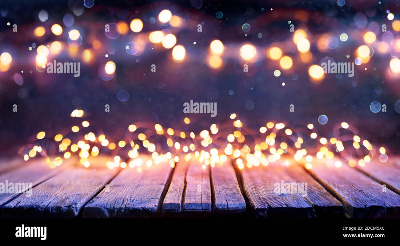 Abstract Christmas background - tavolo in legno con luci a corda sfocate Foto Stock