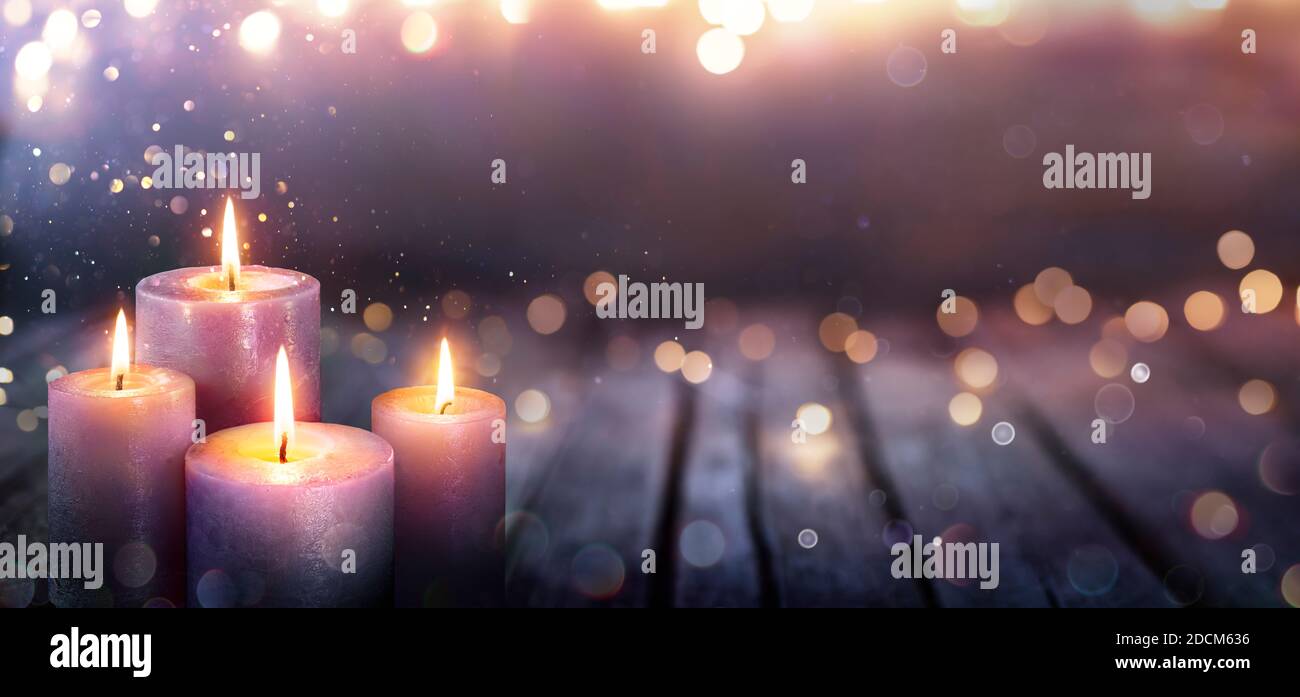 Avvento astratto - quattro candele viola con luci soffici e sfocate E brillare su fiamme Foto Stock