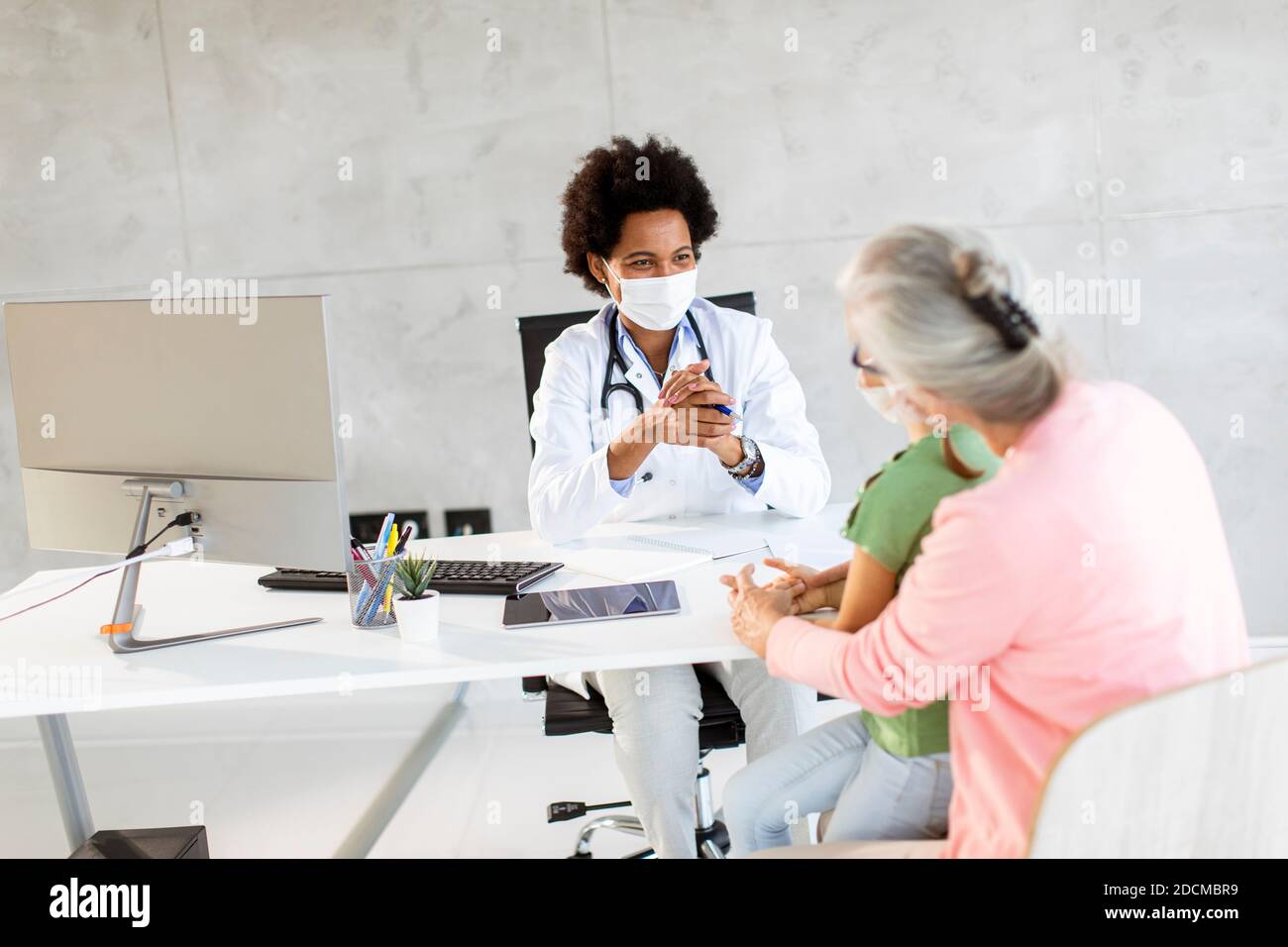 Nonna con maschere facciali protettive con nipotina carina nera medico femminile Foto Stock