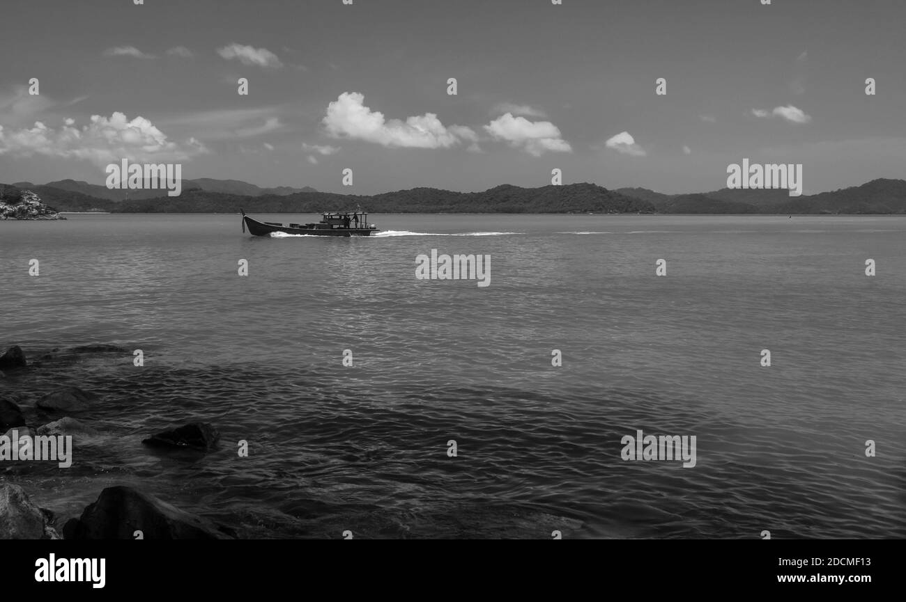 Una barca da pesca passa vicino alla spiaggia. Foto Stock
