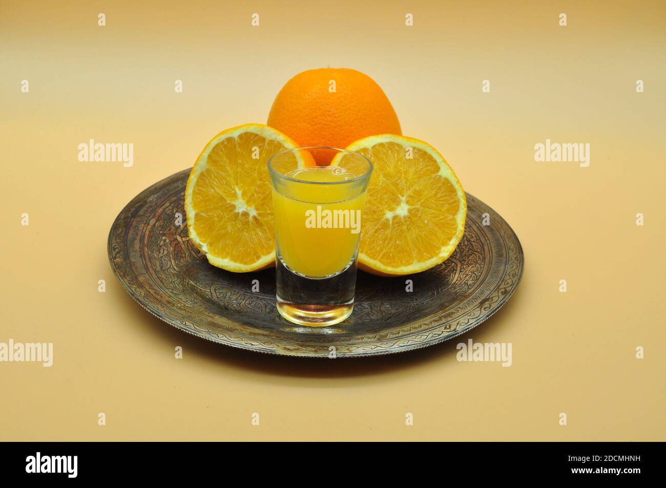 Bicchiere di succo d'arancia fresco e di arance su un neutro sfondo arancione Foto Stock