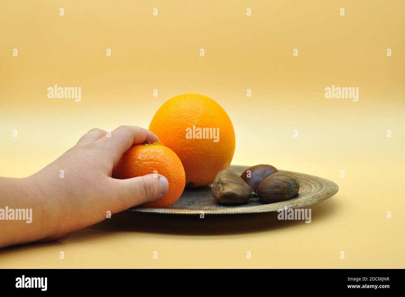 Ancora vita di arance e tangerini poggiano su un elegante e antico piatto d'argento su sfondo arancione neutro Foto Stock