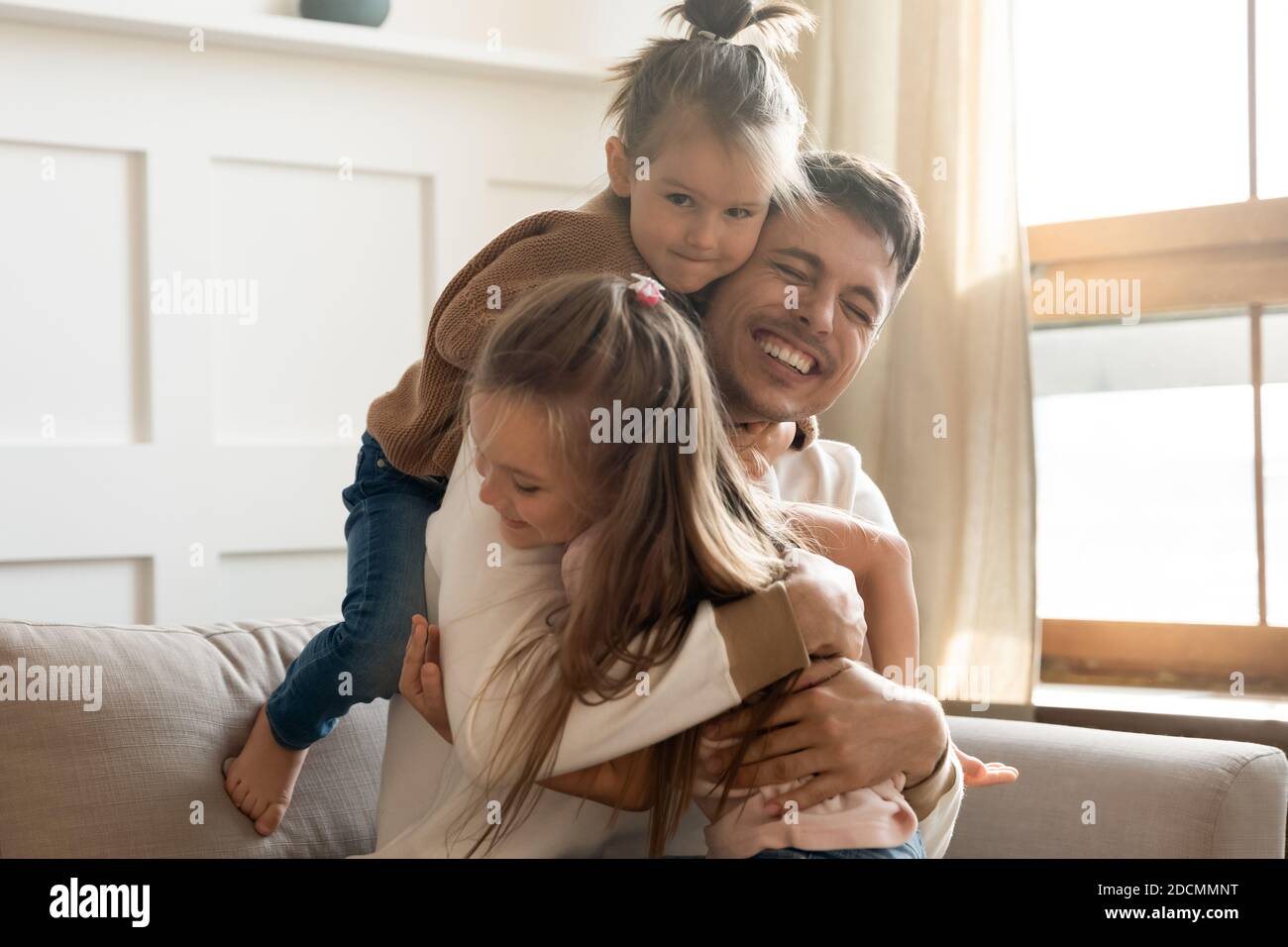 Le piccole figlie che coccolano il papà amorevole si congratulano con lui il giorno felice del Padre Foto Stock