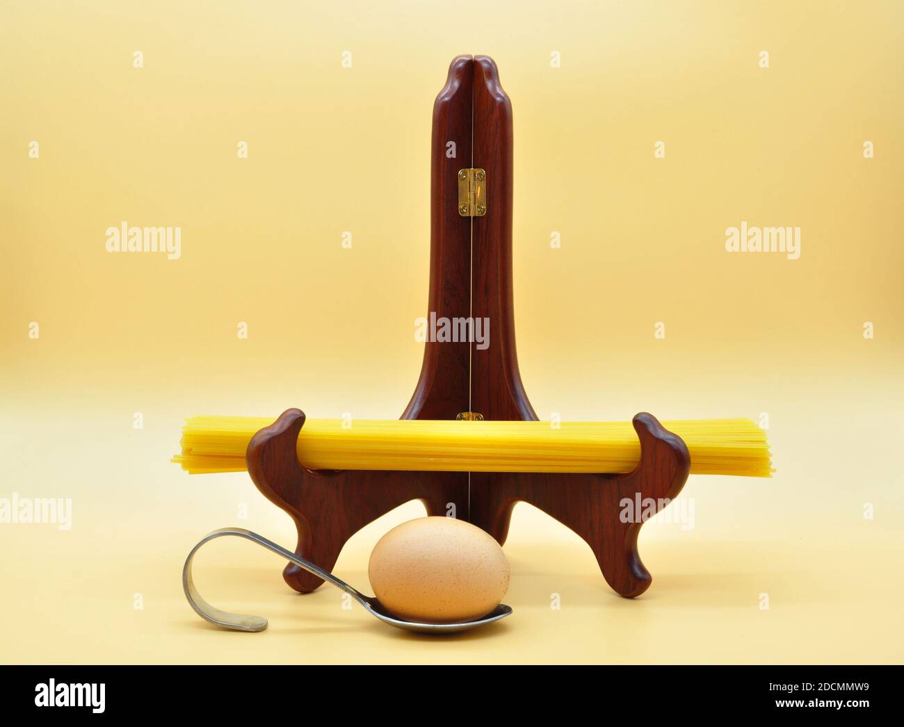 curiosa ed elegante presentazione di spaghetti su supporto in legno e davanti a un uovo su uno strano cucchiaio Foto Stock