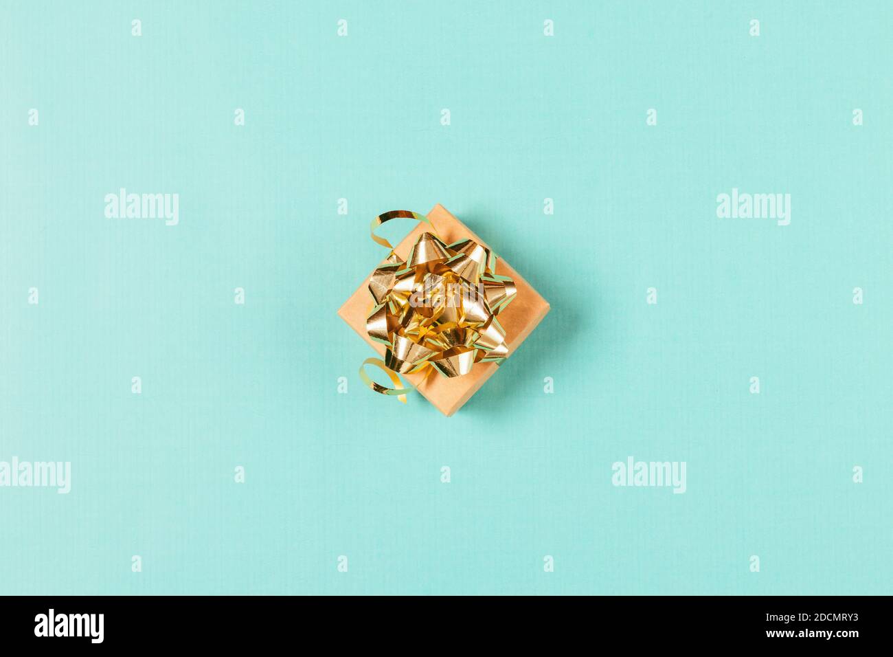 Confezione regalo vista dall'alto con arco in oro e nastri su sfondo azzurro. Foto Stock
