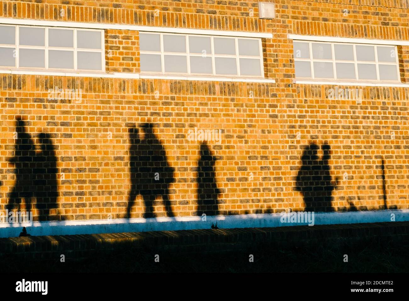 Londra: 22 novembre 2020. Sillouette di persone che camminano e pedalano contro le mura del Brockwell Lodo in un parco molto trafficato Brockwell. I parchi nelle città di Londra sono insolitamente occupati a causa delle restrizioni di Covid-19 e di Lockdown, in modo che le persone si incontrino all'esterno. Foto Stock