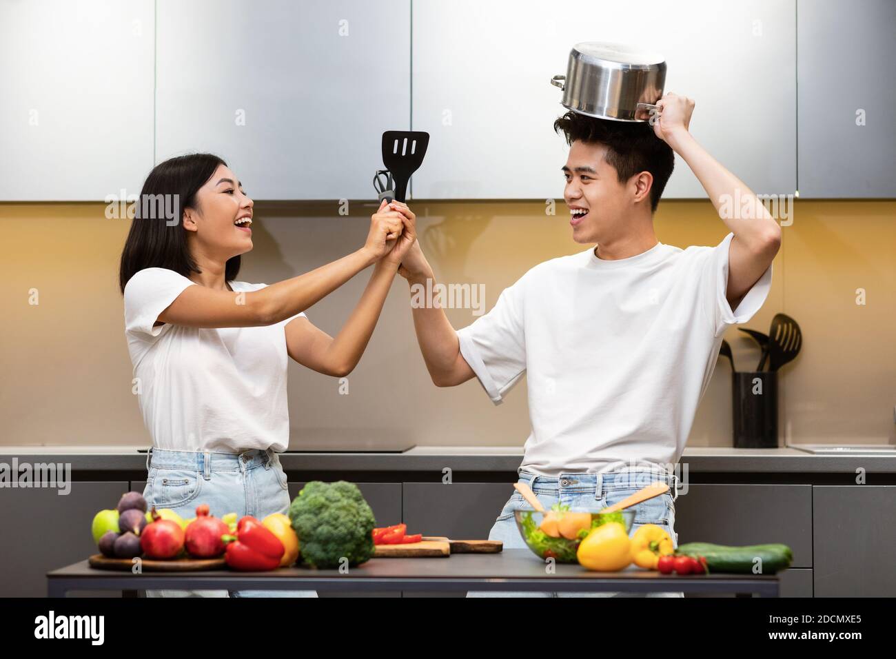 Recinzione della famiglia giapponese con gli attrezzi di cottura che hanno divertimento in cucina Foto Stock