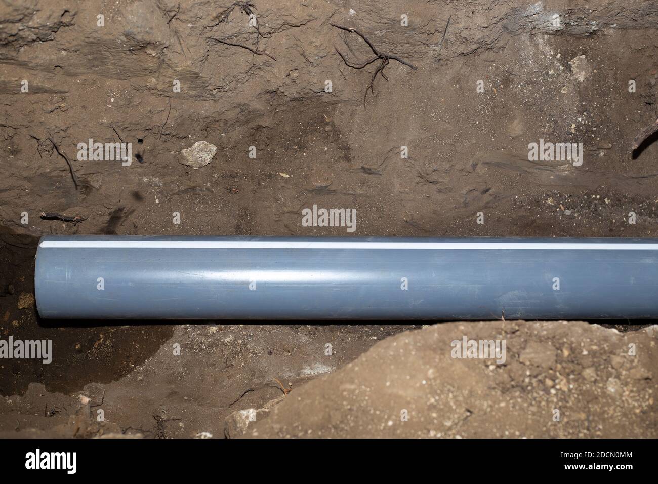 un tubo di drenaggio in plastica si trova in una trincea scavata, costruzione e. comunicazioni Foto Stock