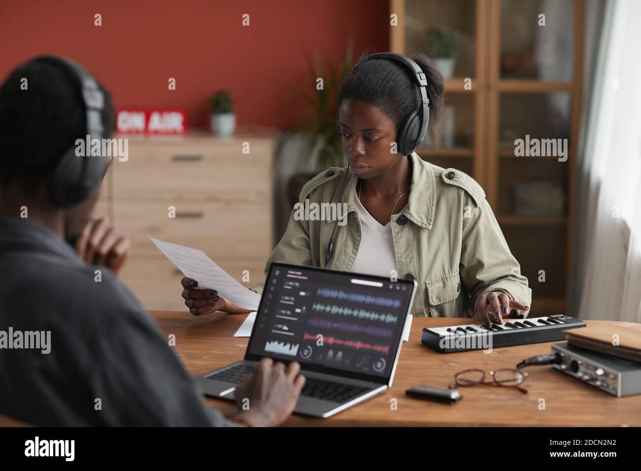 Ritratto di due musicisti afro-americani che compongono musica insieme mentre si siede alla scrivania in studio di registrazione a casa, spazio di copia Foto Stock