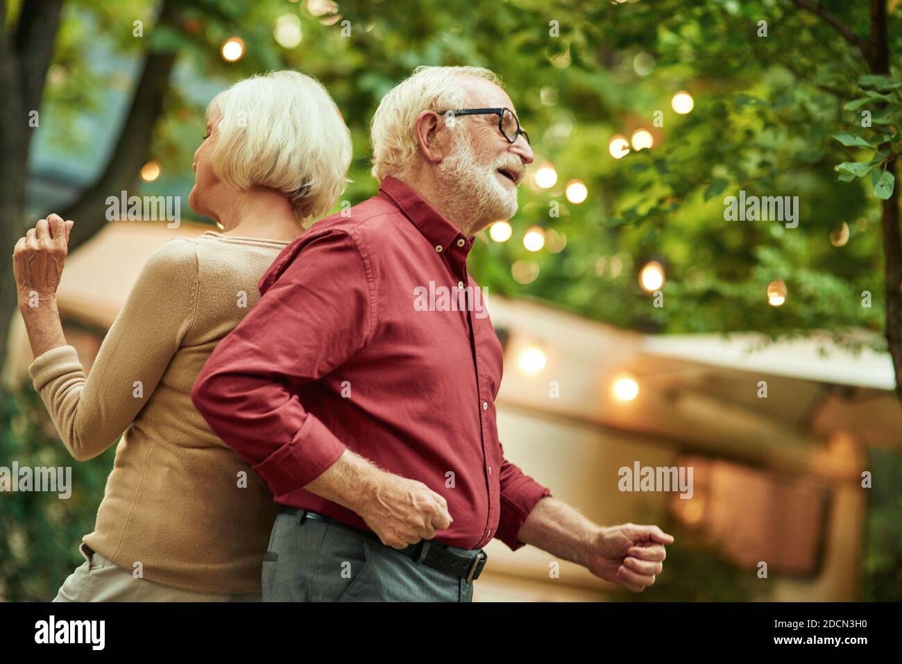 Felice anziana coppia sposata divertirsi durante una danza grovy con il loro campervan sullo sfondo. Concetto di viaggio Foto Stock