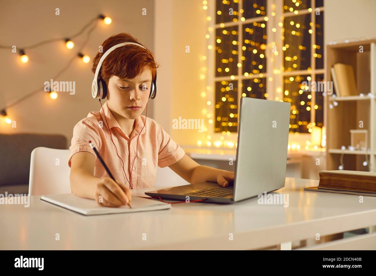 Scolaro serio che rimane a casa sulle vacanze invernali e che si concentra su studia utilizzando il suo laptop Foto Stock