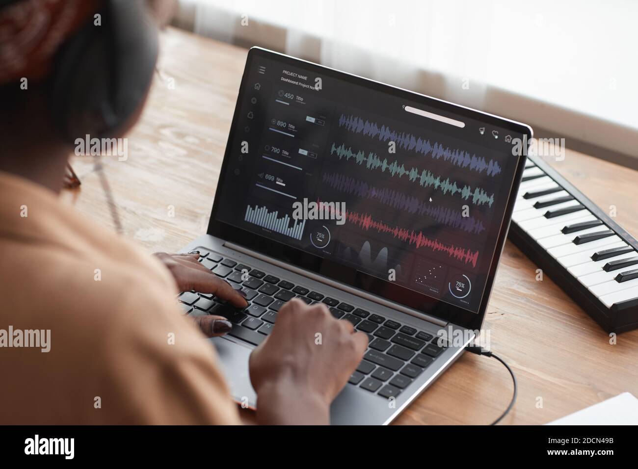 Primo piano di una musicista afro-americana che utilizza un computer portatile con software di editing audio mentre componi musica a casa, spazio di copia Foto Stock