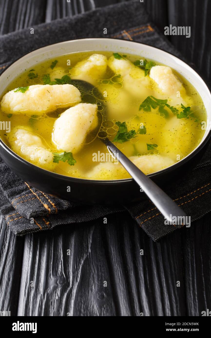 Zuppa di semola Dumpling Griessnockerlsuppe molto deliziosi sono questi gnocchi in zuppa di verdure chiaro primo piano in un piatto sul tavolo. Verticale Foto Stock