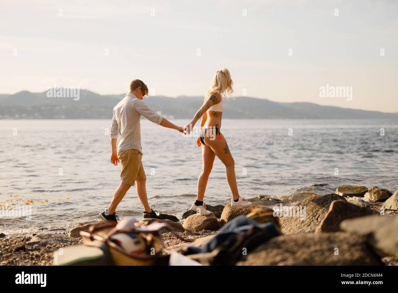 Donna che tiene le mani che cammina con il ragazzo sulle rocce Foto Stock