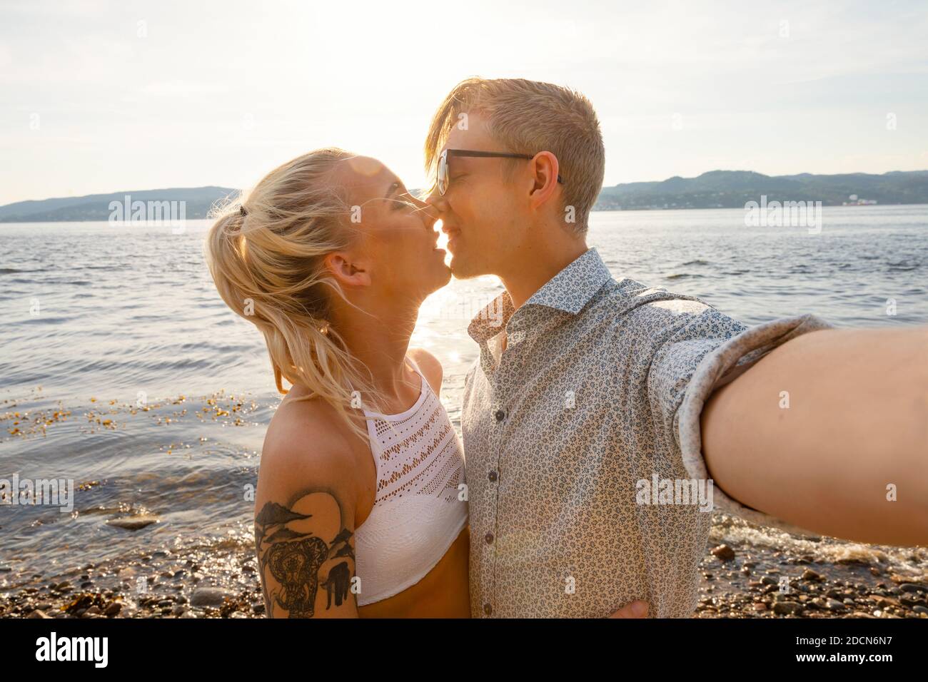 Felice giovane coppia Kissing e prendendo Selfie a Beach Foto Stock