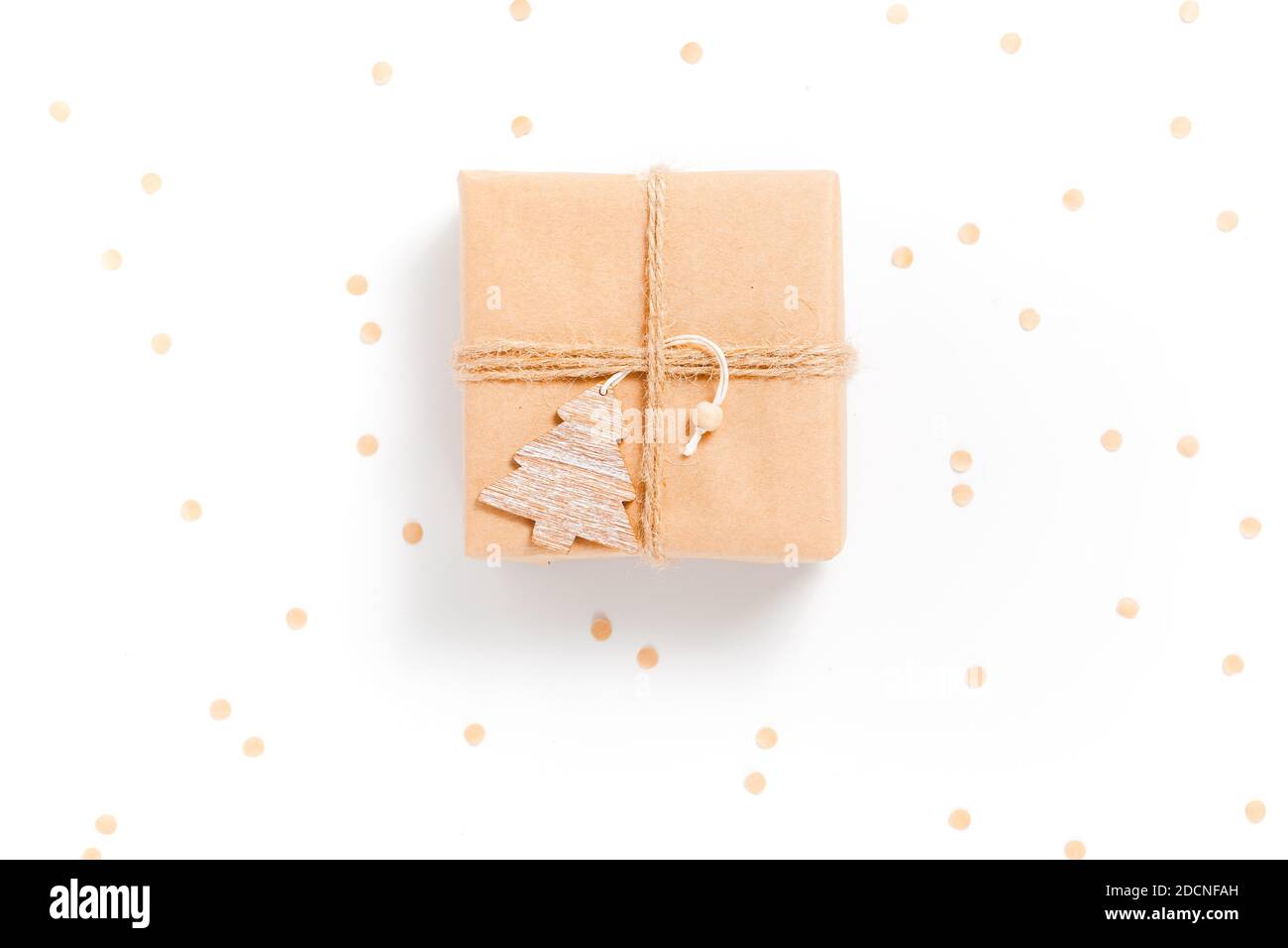 Piccola scatola regalo avvolta in carta artigianale con Natale in legno decorazioni ad albero su sfondo bianco Foto Stock