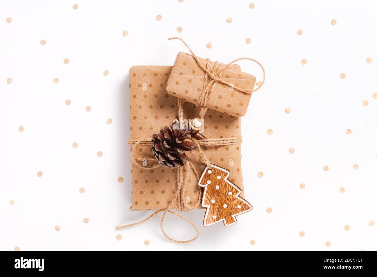 Due scatole regalo avvolte in carta artigianale con decorazioni su sfondo bianco decorato con confetti Foto Stock