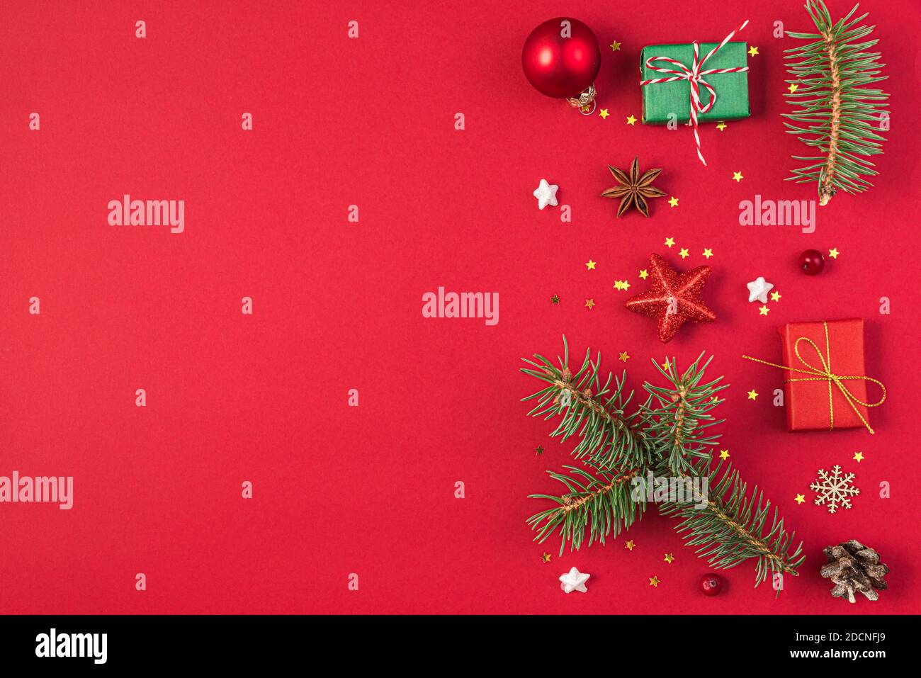 Composizione natalizia su sfondo rosso fatta di doni, abeti, decorazioni. Natale, inverno, concetto di anno nuovo. Disposizione piatta, vista dall'alto con spazio per la copia Foto Stock