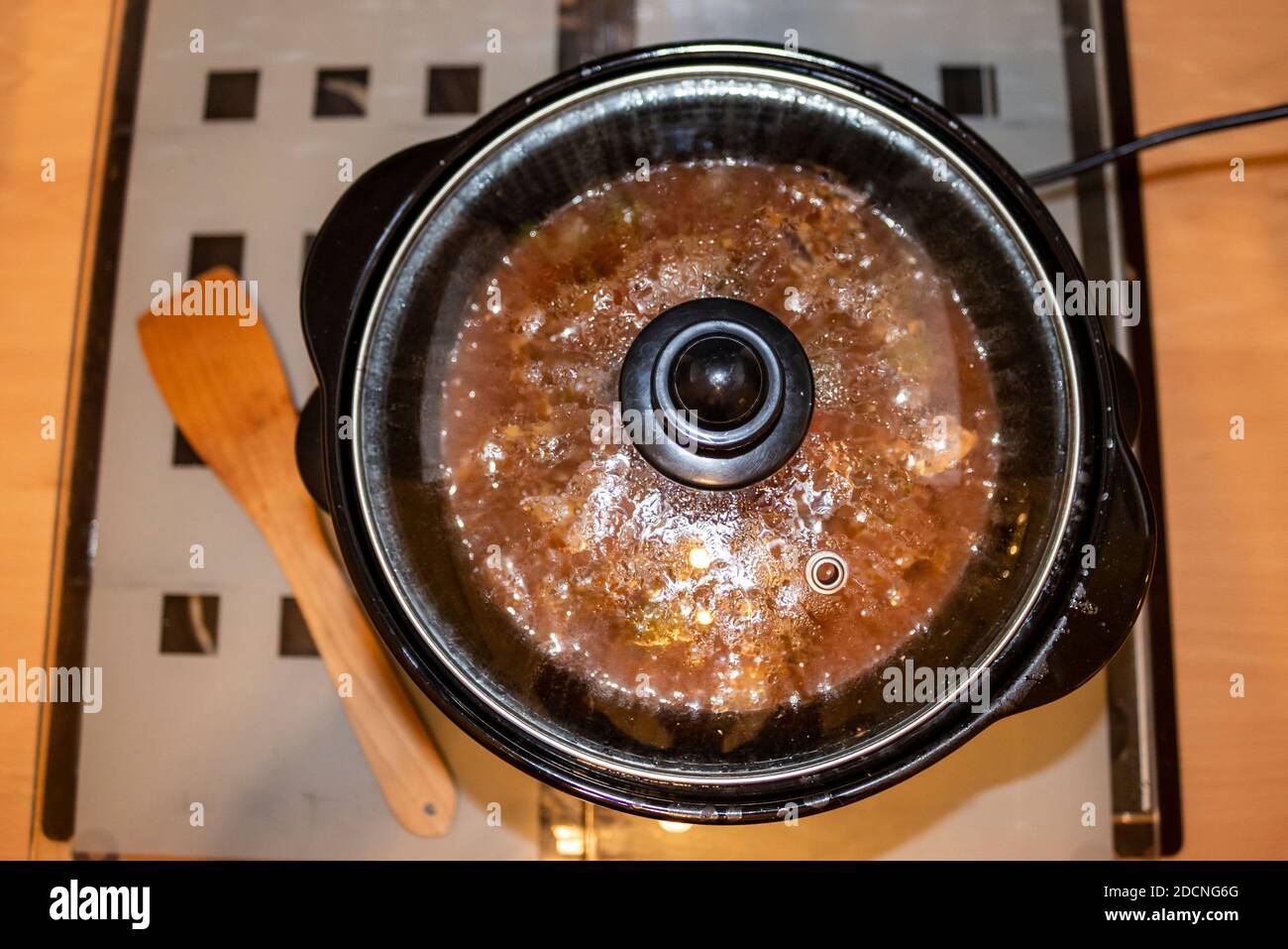 Cucina lenta con cottura in casseruola di manzo. Cucina casalinga autentica con spatola. Succhi di sugo con verdure. Pentola Foto Stock