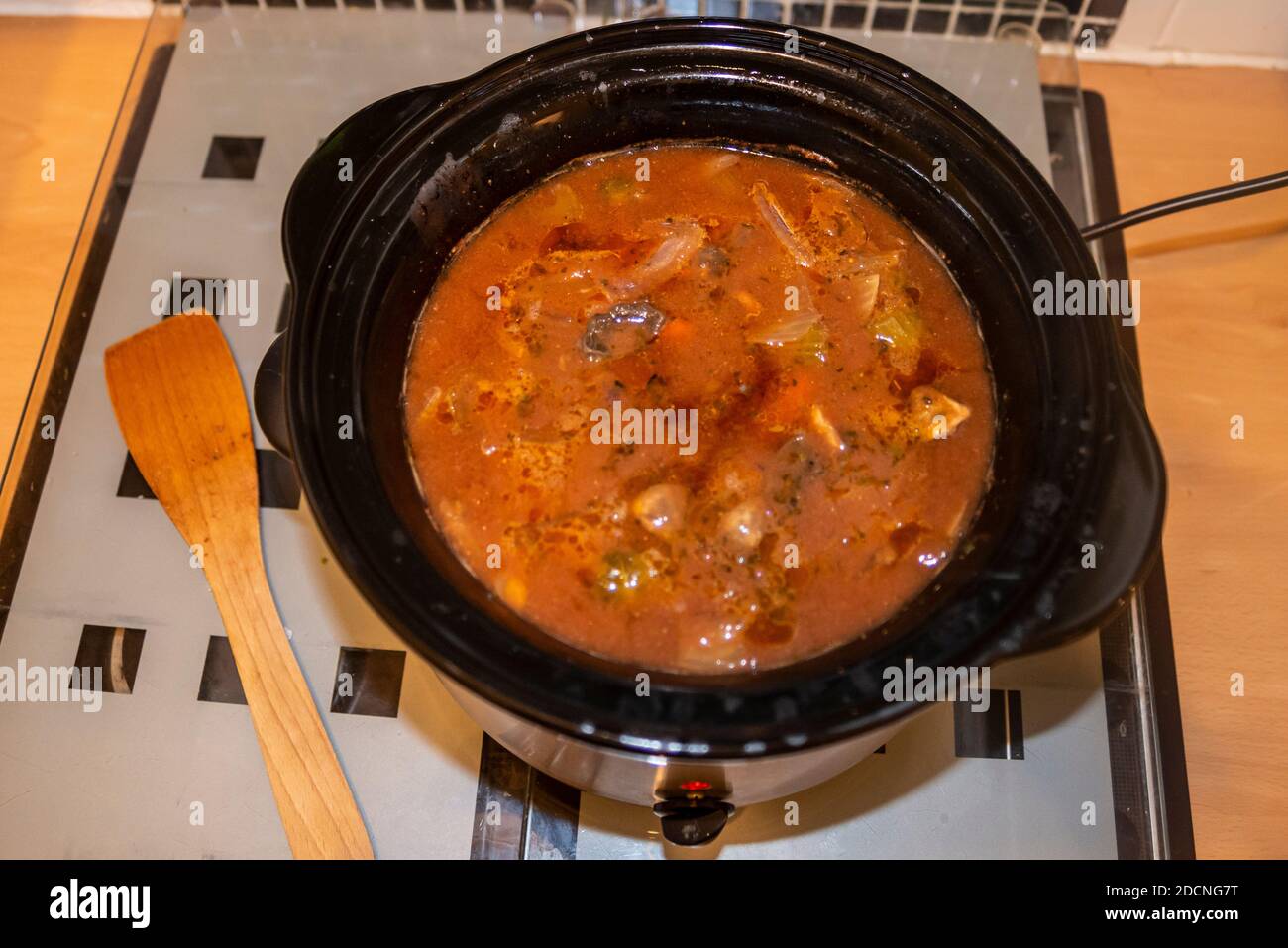 Cucina lenta con cottura in casseruola di manzo. Cucina casalinga autentica con spatola. Succhi di sugo con verdure. Pentola Foto Stock