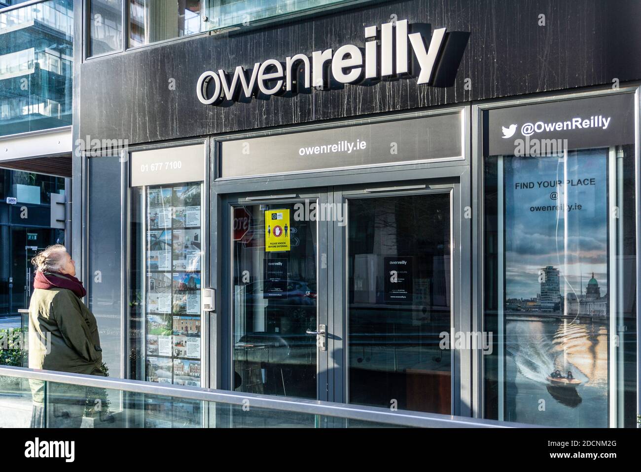 Proprietà in vendita.UNA donna che studia i prezzi della casa presso un'agenzia immobiliare a Forbes Street in Grand Canal Dock a Dublino, Irlanda. Foto Stock