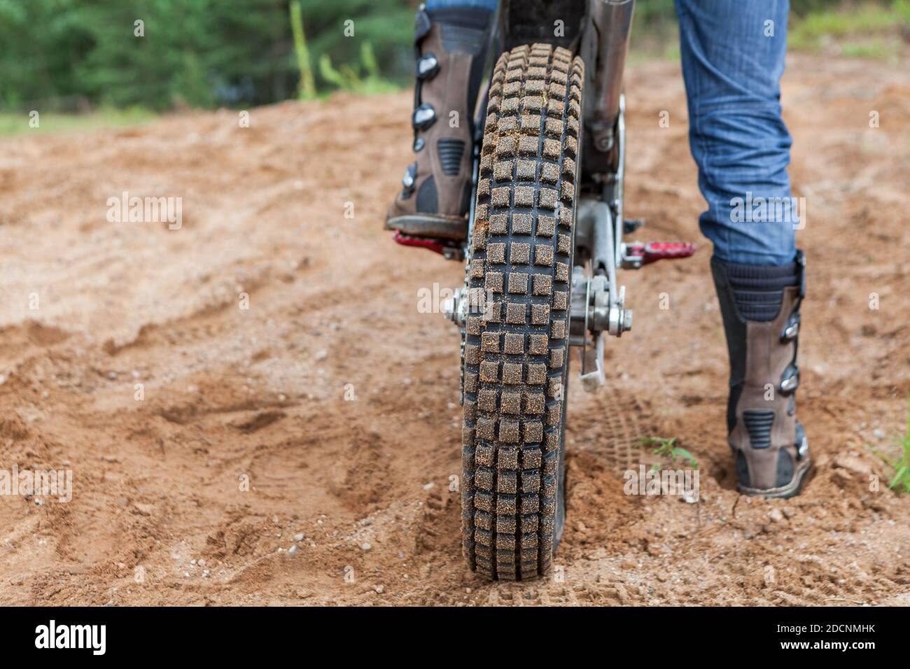 Motociclista con stivali in piedi su spina di moto sporco su pista di sabbia, copyspace Foto Stock