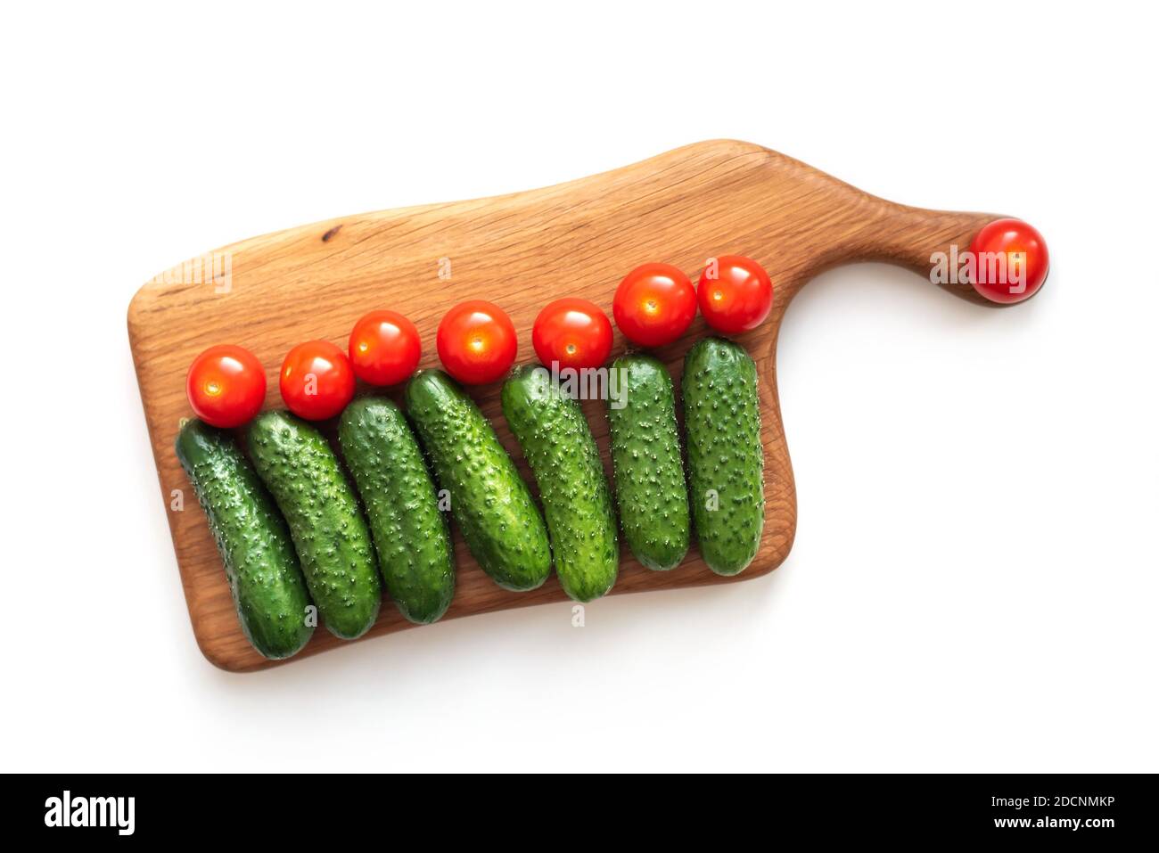 Layout creativo piatto di verdure fresche cetrioli e pomodori su tavola di legno su bianco Foto Stock
