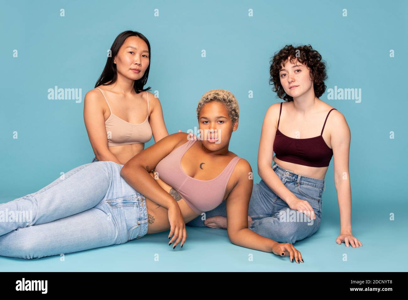 Tre ragazze contemporanee riposanti di etnie asiatiche, caucasiche e africane Foto Stock