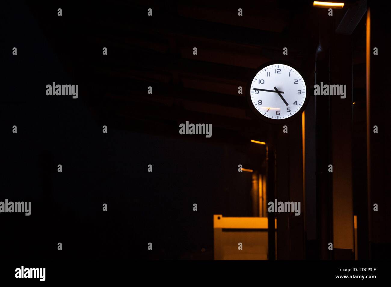 Orologio analogico sulla piattaforma di una stazione ferroviaria centrale di notte, durante una serata buia, che indica l'ora esatta. Immagine della piattaforma di una t Foto Stock