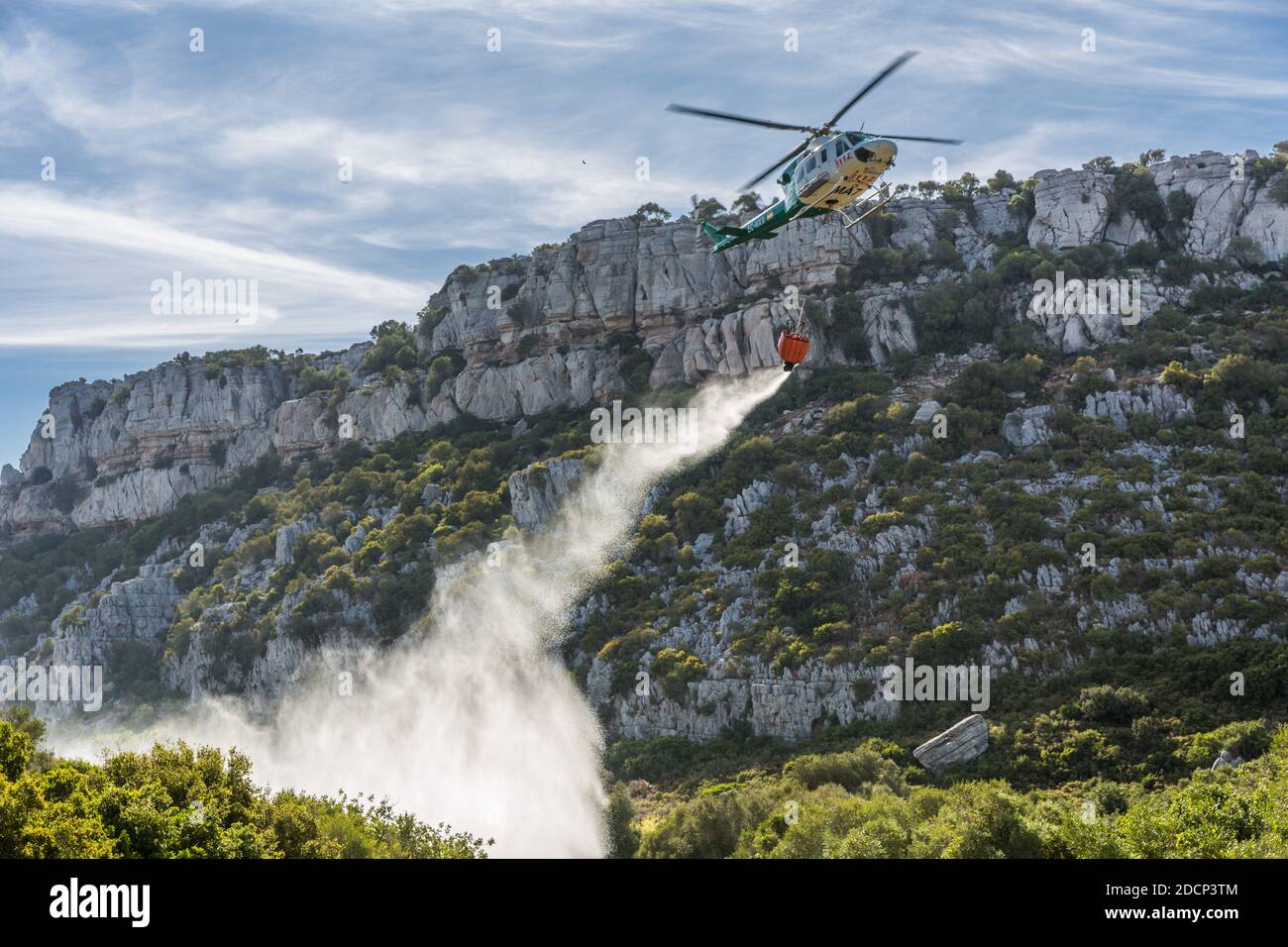 Bomberos (vigili del fuoco) che mette un fuoco a Canuto De la Utrera, usando un secchio d'acqua su un elicottero Foto Stock