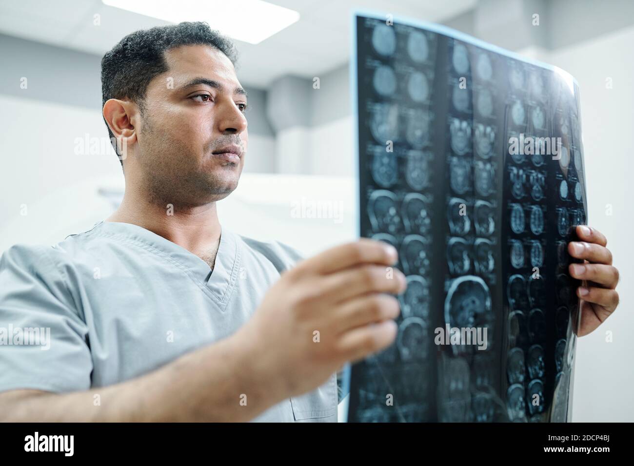 Radiologo contemporaneo a razze miste in uniforme che guarda l'immagine radiografica di paziente Foto Stock