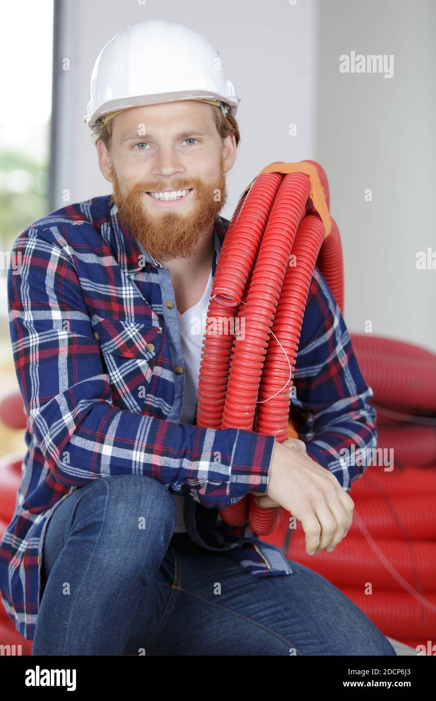 ritratto di un appaltatore che detiene un condotto elettrico rosso Foto Stock