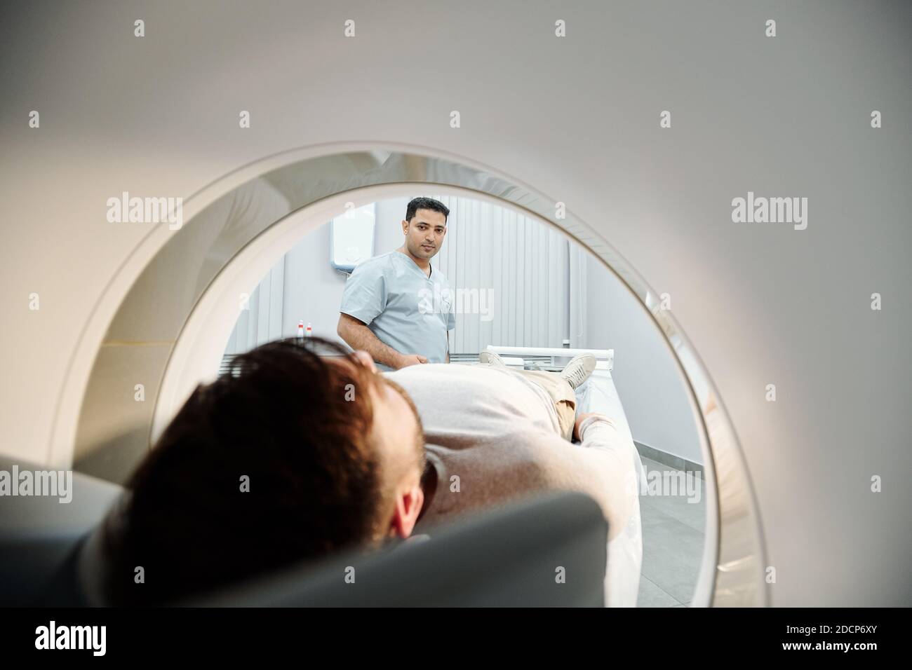 Giovane medico di razza mista in uniforme guardando paziente in ultra macchina sonora Foto Stock