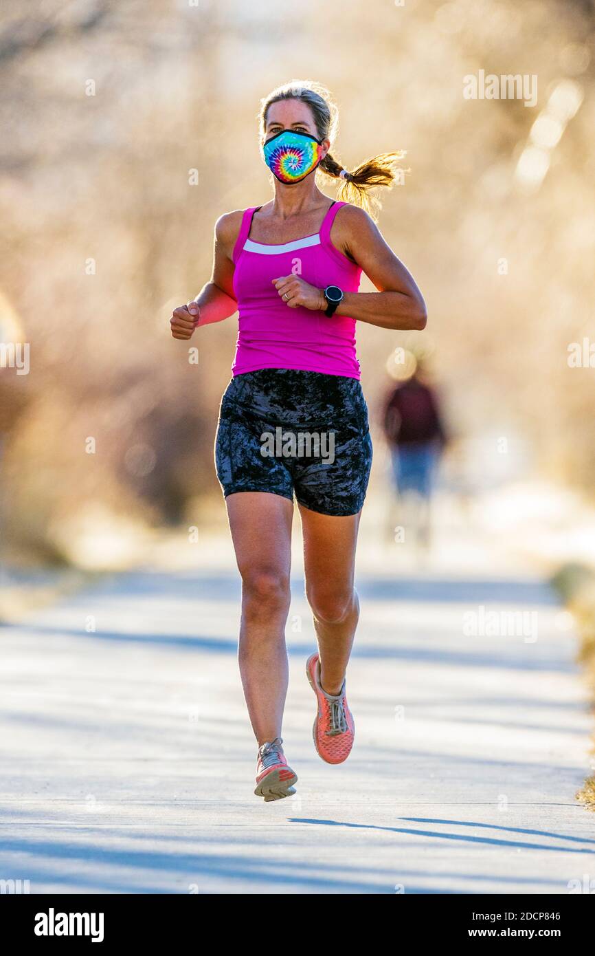 Attraente; vestibilità; donna di mezza età che indossa maschera protettiva; corsa su sentiero lastricato; Salida; Colorado; USA Foto Stock
