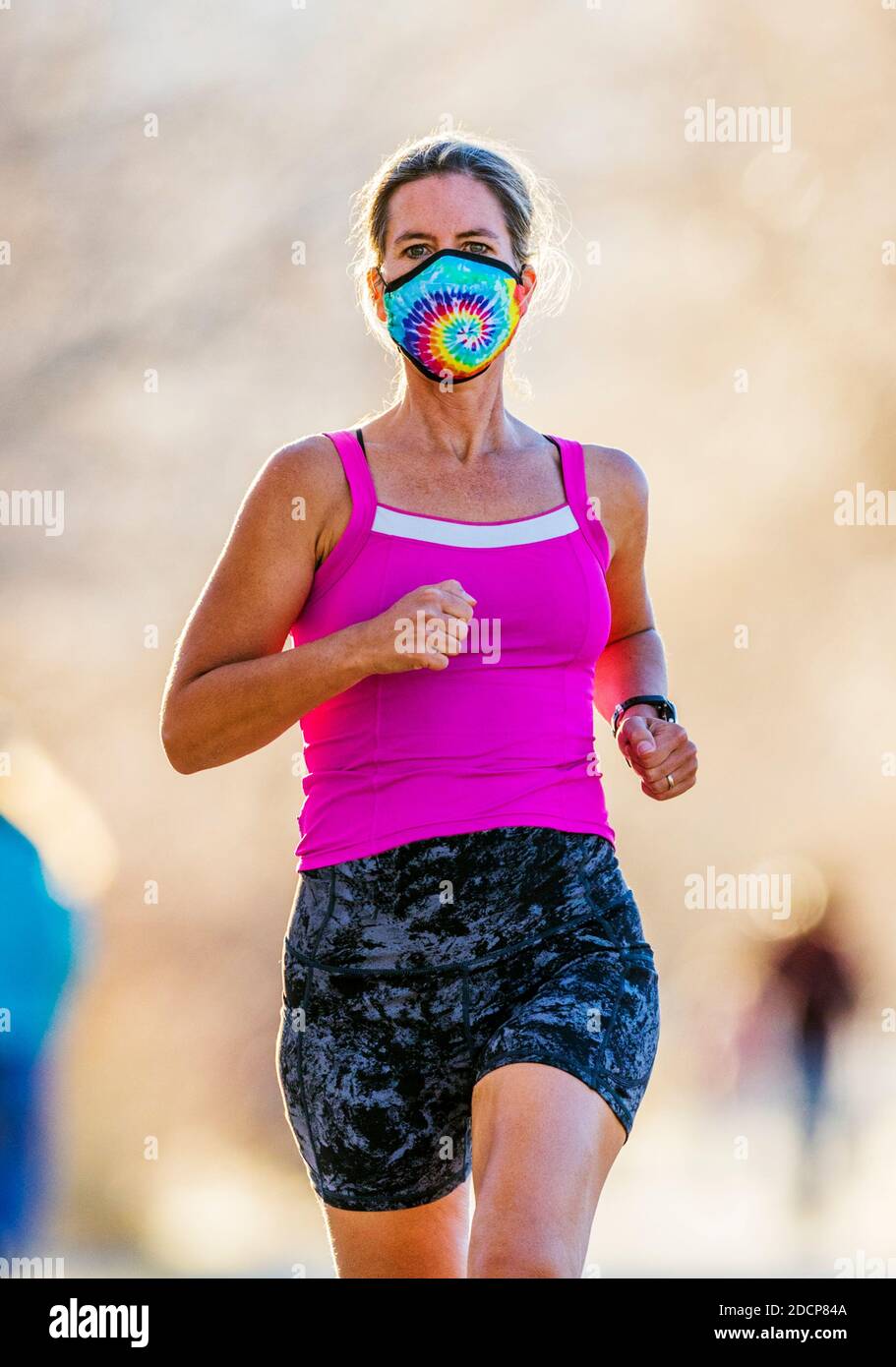 Attraente; vestibilità; donna di mezza età che indossa maschera protettiva; corsa su sentiero lastricato; Salida; Colorado; USA Foto Stock