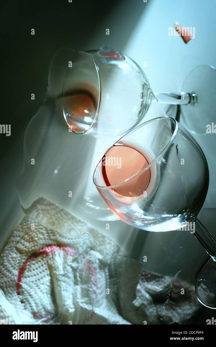 Dopo la festa, interpretazione astratta da una prospettiva insolita e confusa con due calici caduti, vino rosso lasciato e un napk di carta sporco Foto Stock