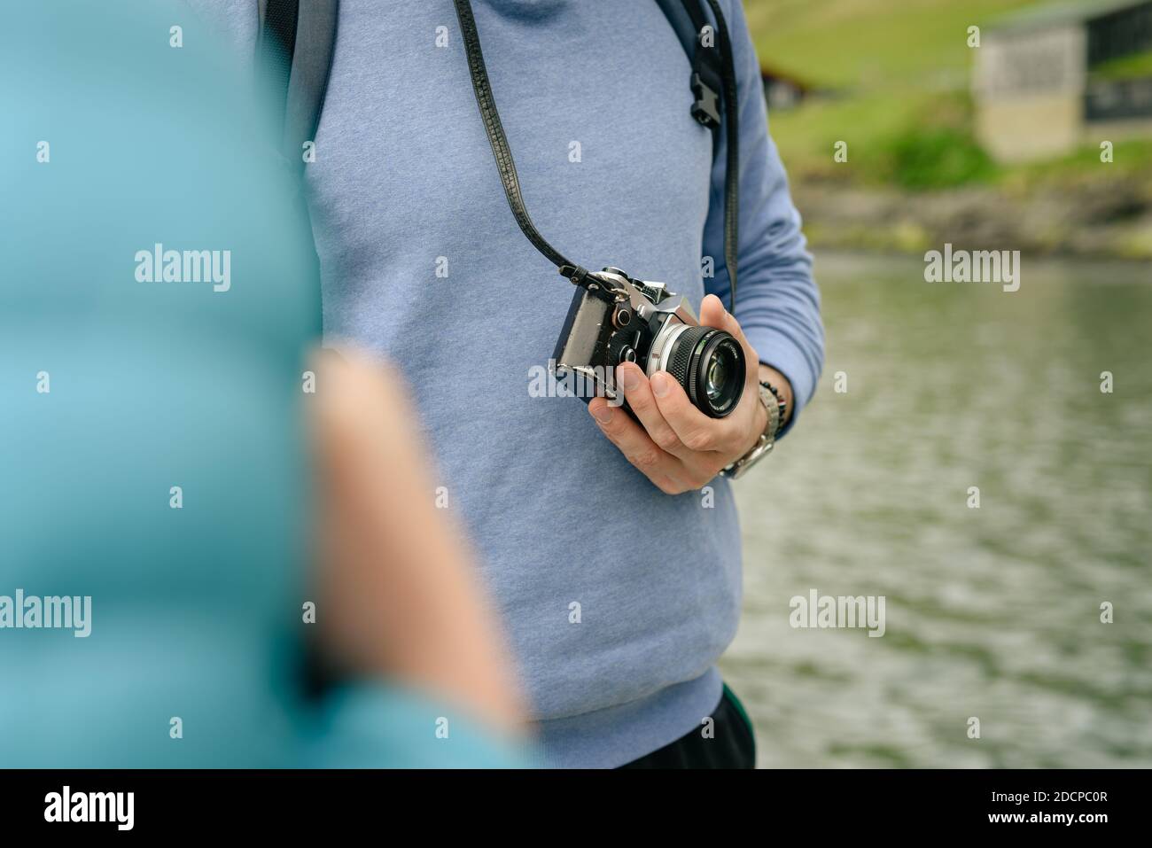 Messa a fuoco morbida del turista anonimo con la macchina fotografica che riposa sopra costa vicino al mare Foto Stock