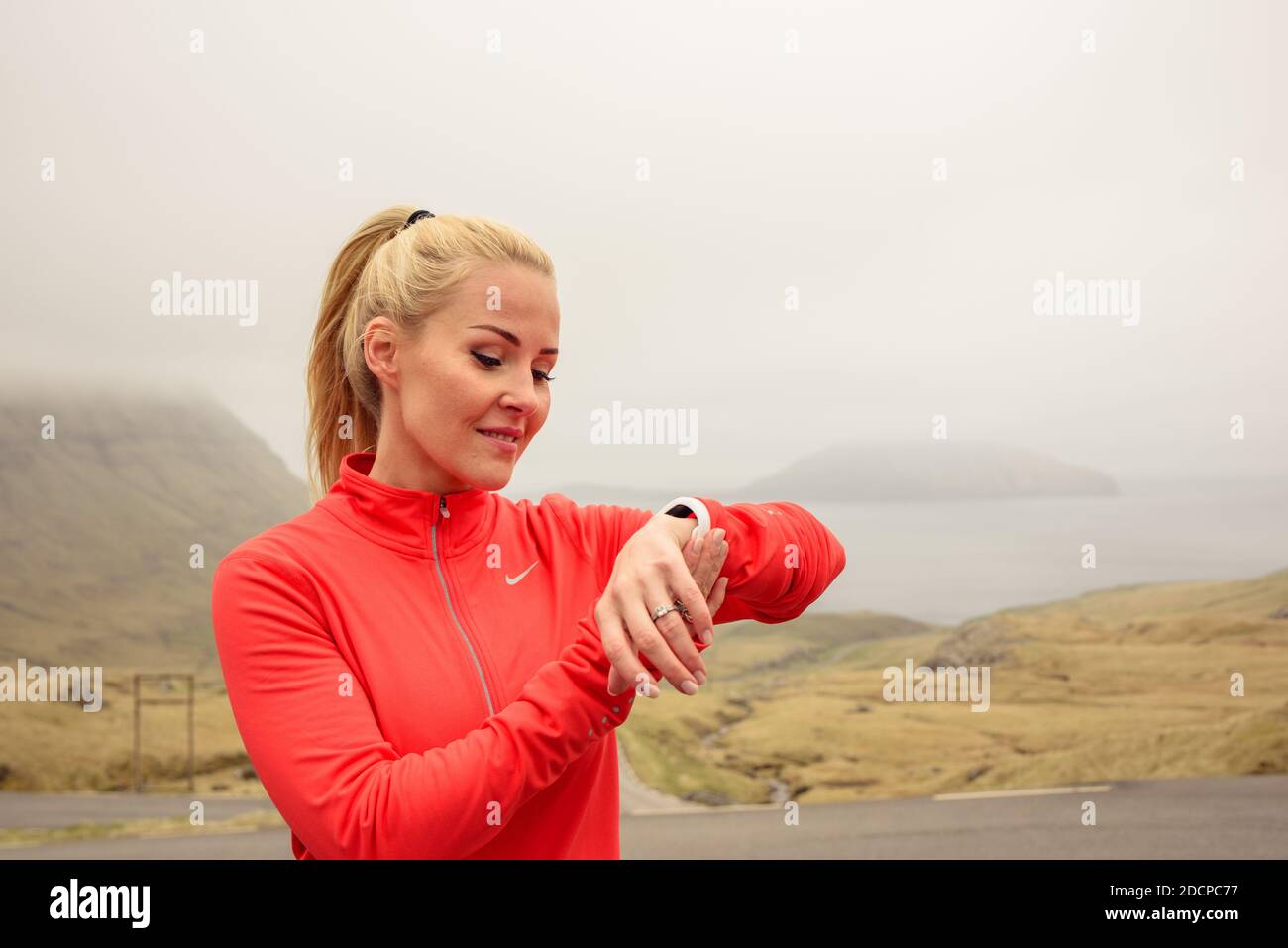 Atleta che controlla l'impulso su Smart Watch durante l'allenamento fitness il giorno del nebbio Foto Stock