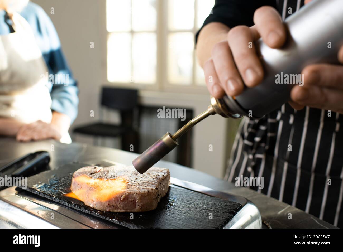 Mano di giovane allenatore di cucina maschile in grembiule pezzo di fumo di manzo bollito Foto Stock