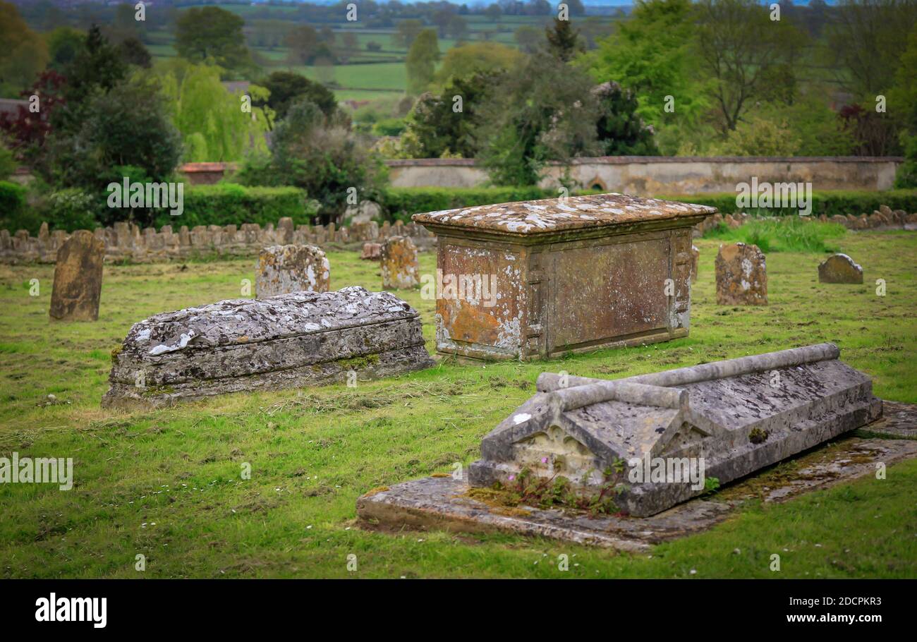 Le cripte dei prati in un cimitero parrocchiale del Vecchio mondo presso la chiesa di St Michael & All Angels si affacciano su un paesaggio della campagna inglese a East Coker, Inghilterra Foto Stock