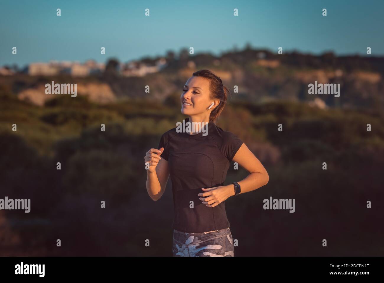 Atleta giovane e slim da donna che corre con tracker per il fitness o orologio intelligente. Corsa con le cuffie Foto Stock