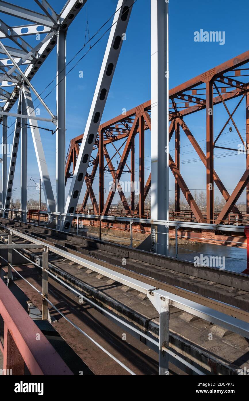 Primo piano del metallo di un ponte ferroviario su un fiume con un passaggio pedonale consentito. Ponte ferroviario sul fiume Kitoy in Siberia, Russia Foto Stock