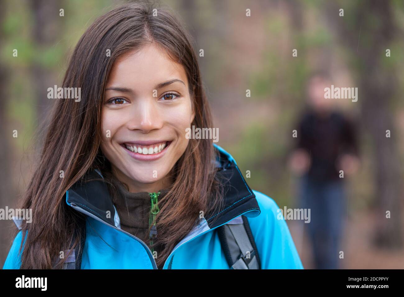Donna sana escursioni all'aperto. Felice giovane ragazza escursionista che cammina nel bosco con un gruppo di amici. Sorridente turista cinese. Foto Stock