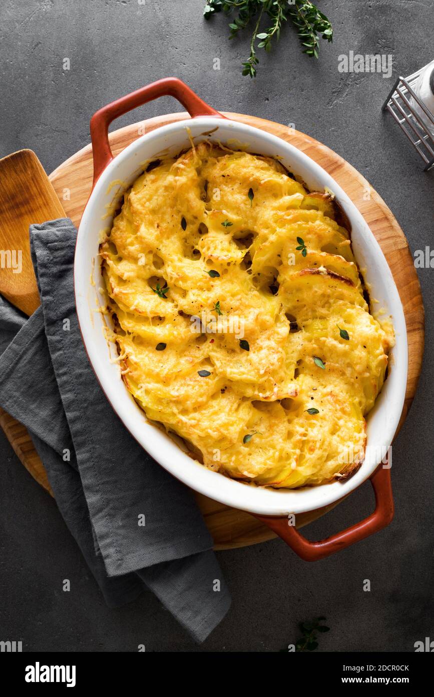 Gratin di patate. Casseruola di patate appena sfornata su tavolo scuro, vista dall'alto, primo piano. Foto Stock