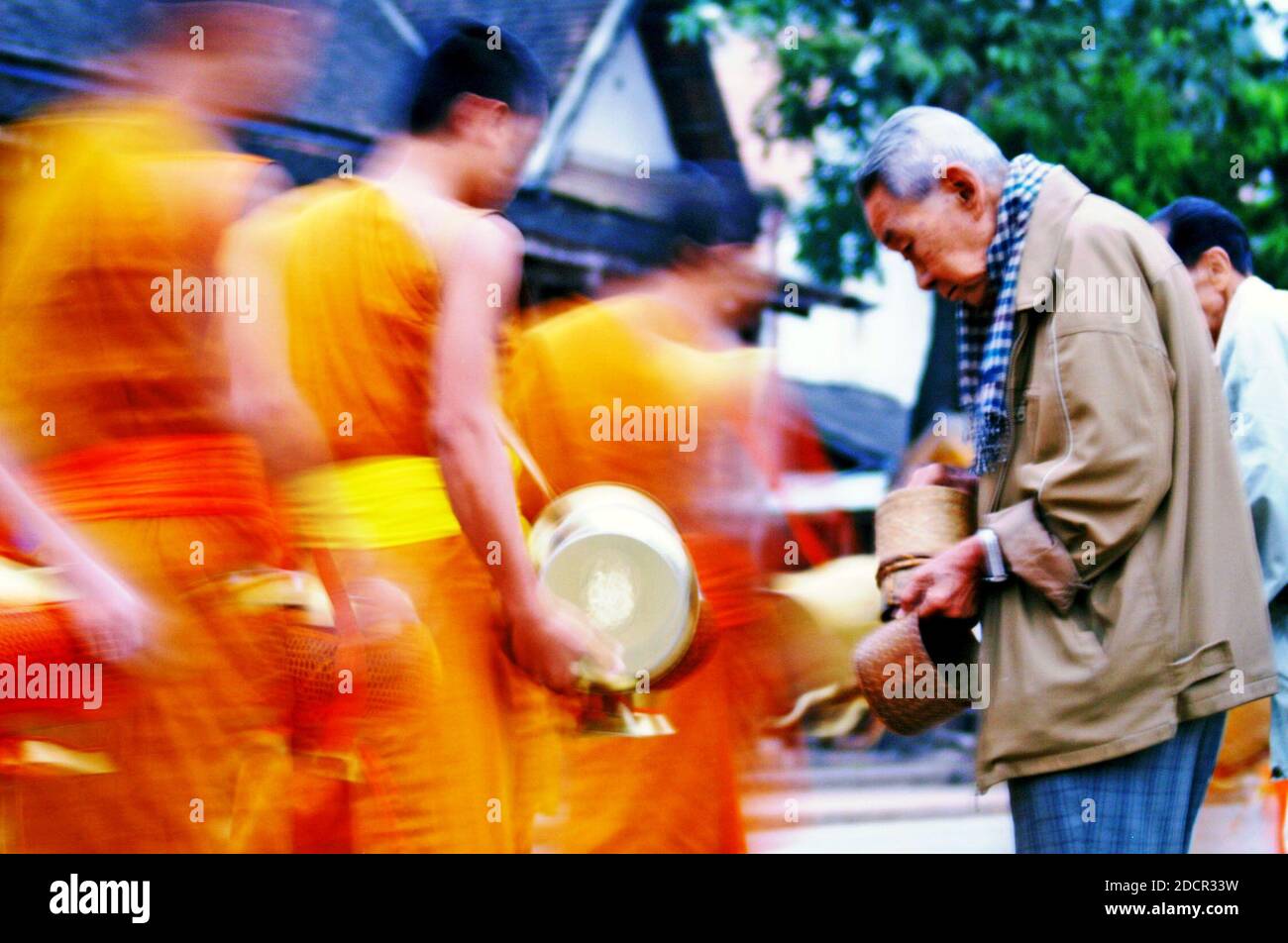 I giovani monaci scendono per le strade per le loro elemosine mattutine a Luang Prabang, Laos. La tradizione buddista vede centinaia di monaci uscire dai templi mentre si fanno strada lungo la strada dove i locali li nutrono mettendo riso nelle ciotole che portano. Foto Stock