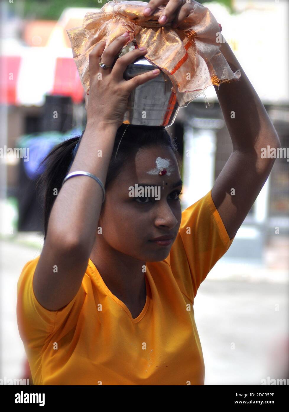 Ritratto di un giovane devoto indù che porta un'urna di latte come offerta durante le tradizionali celebrazioni del Thaipusam. Foto Stock