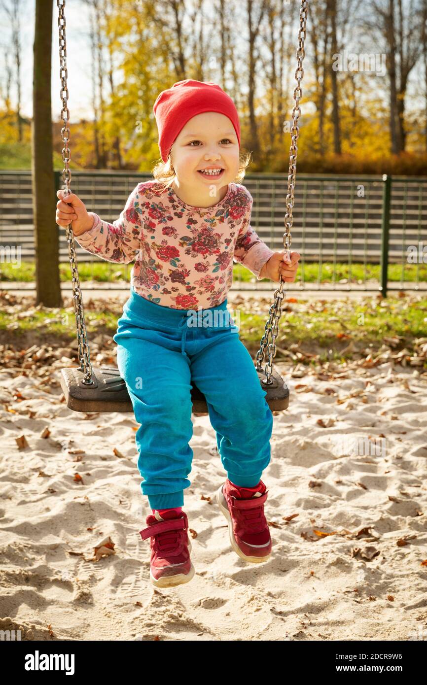 Carino bambina su un'oscillazione in un parco giochi Foto Stock